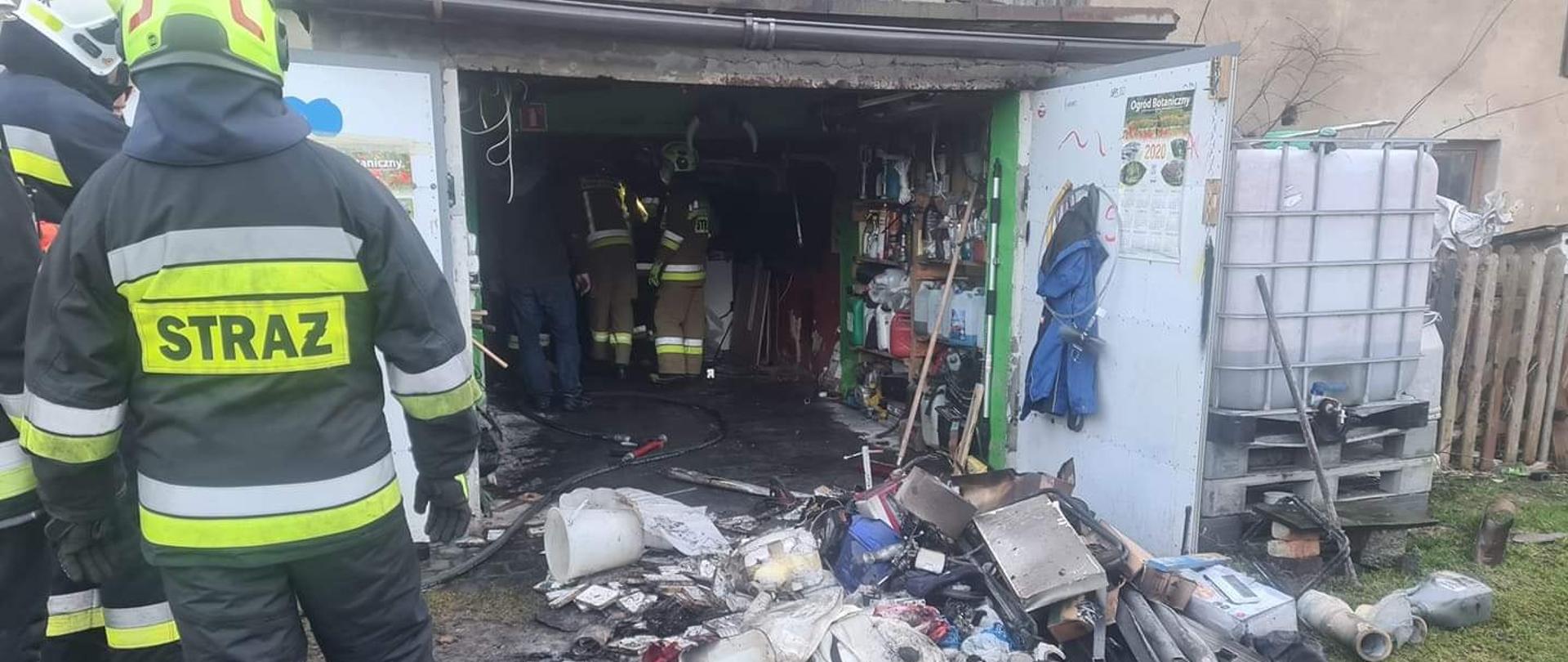 Widać budynek gospodarczy, na zewnątrz spalone materiały