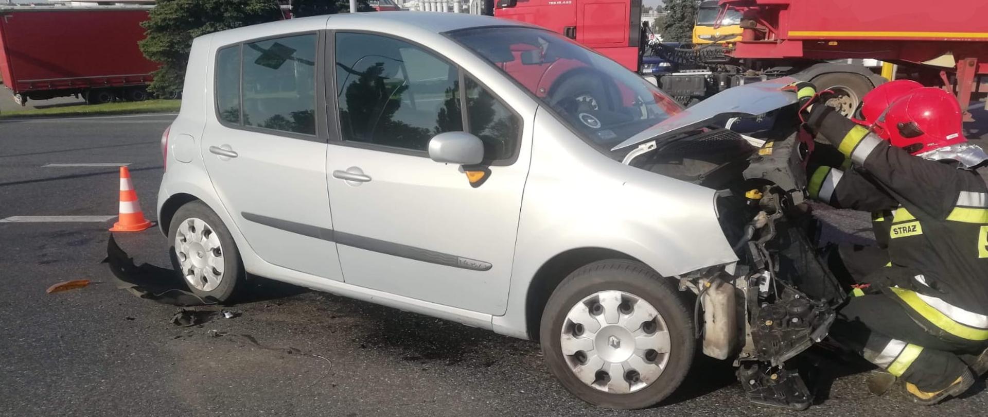 Dwóch strażaków odłączających akumulator w rozbitym pojeździe osobowym