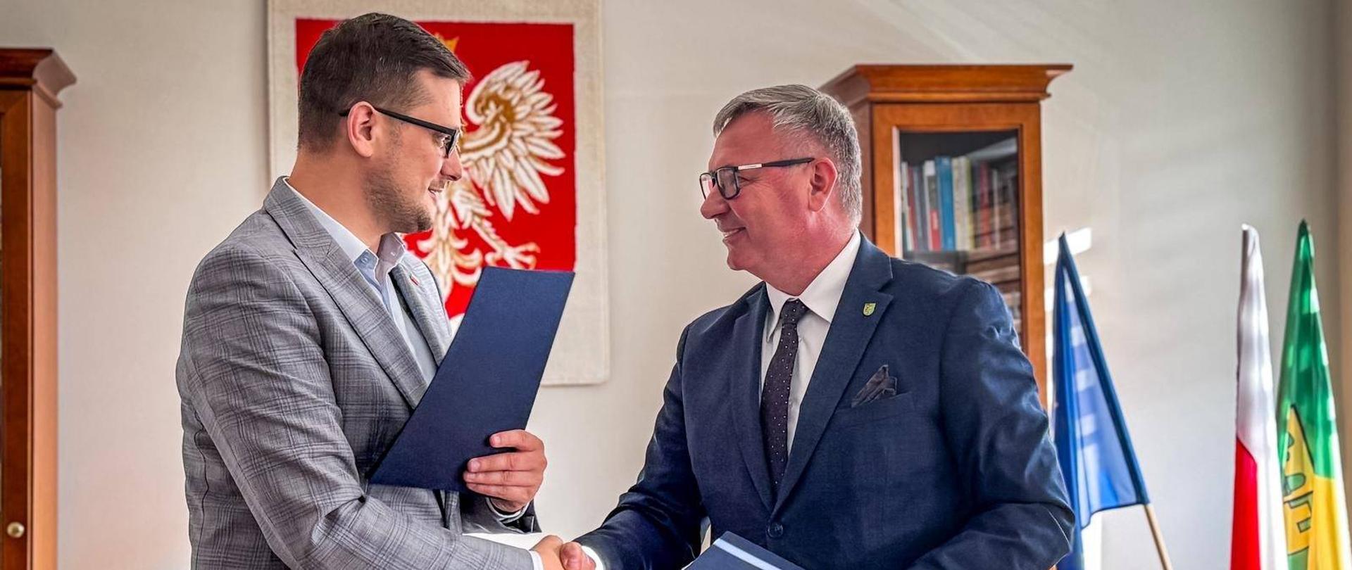 Wojewoda Michał Sztybel ściska dłoń z Wójtem Januszem Jedlińskim po podpisaniu umowy na dofinansowanie.