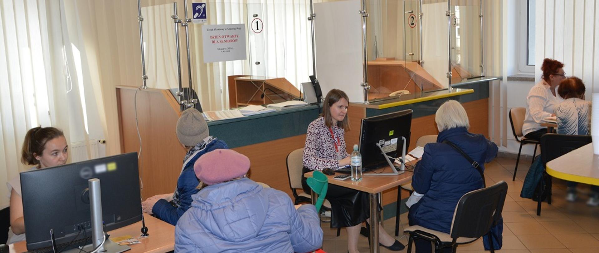 Przy stolikach siedzą eksperci KAS. Przed nimi są klienci.