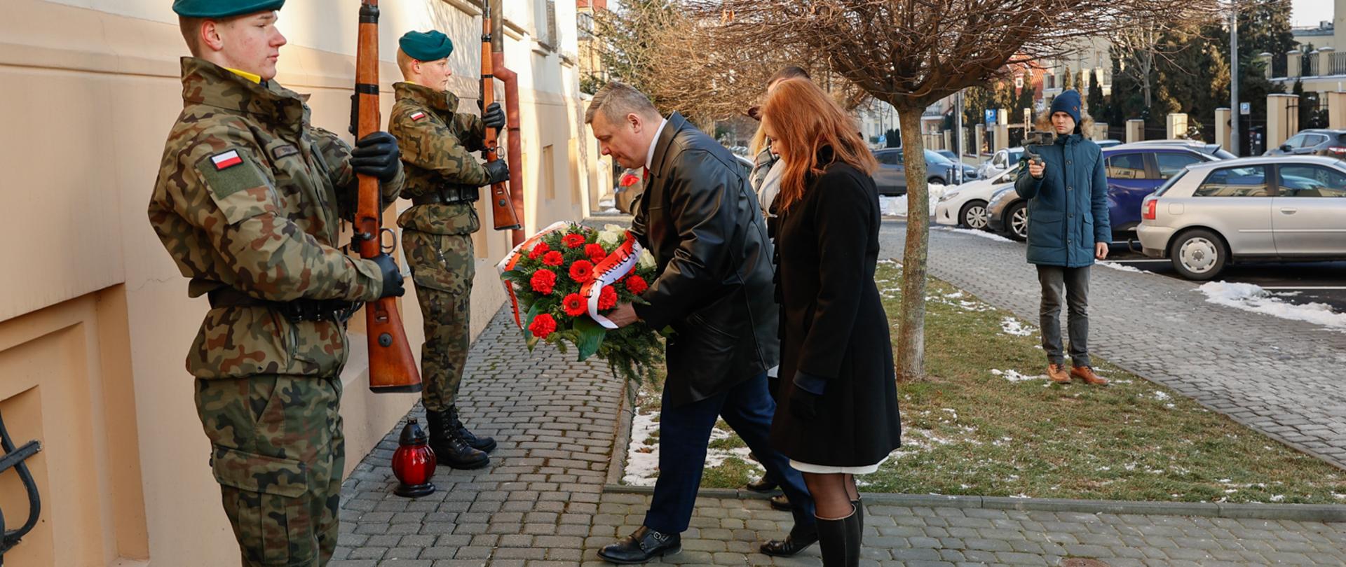 Wicewojewoda Robert Gmitruczuk w asyście Dyrektor Generalnej składa wieniec pod tablicą upamiętniającą gen. Ryszarda Kuklińskiego. 