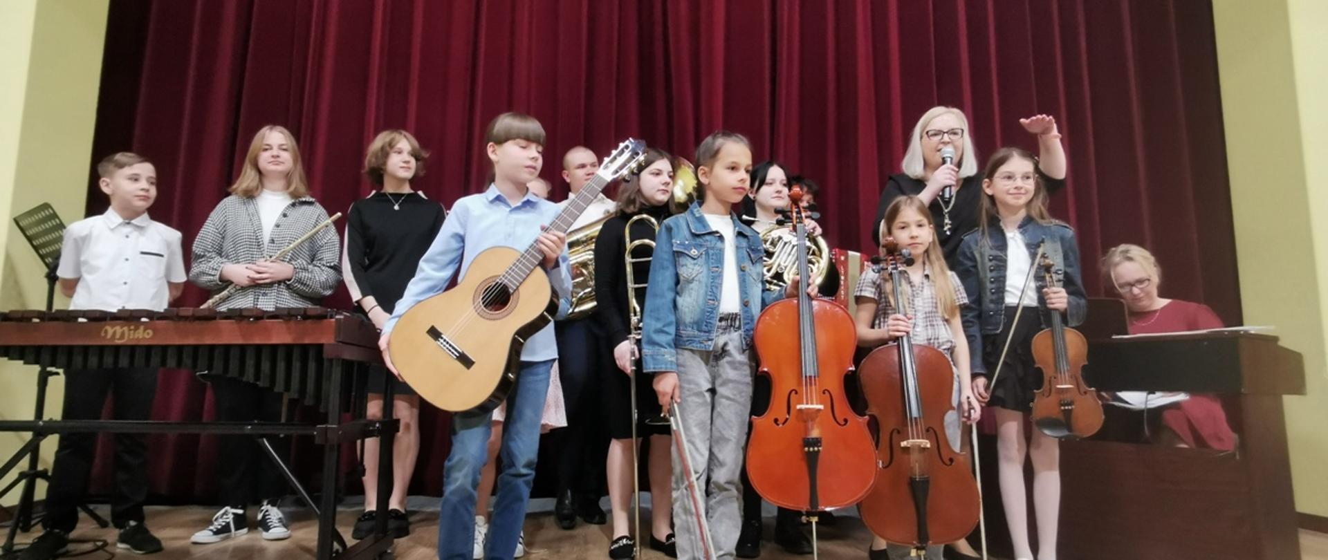 Uczniowie szkoły muzycznej z instrumentami na scenie