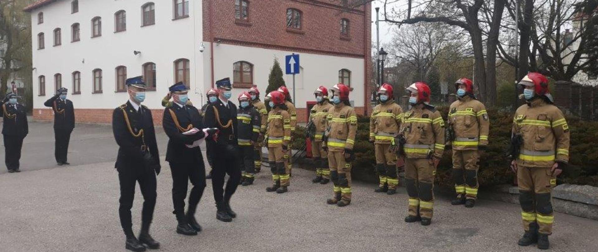 Zdjęcie przedstawia funkcjonariuszy KM PSP Olsztyn w trakcie uroczystych zbiórek z podniesieniem flagi państwowej na maszt