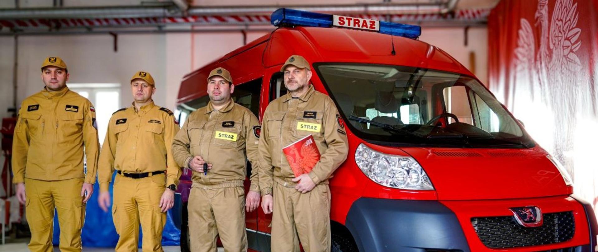 Na zdjęciu widać busa marki Peugeot Boxer przy którym stoi komendant powiatowy i zastępca oraz strażacy OSP