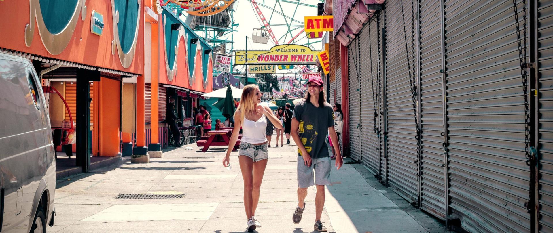 Fotografia przedstawiająca kobietę i mężczyznę spacerujących po parku rozrywki