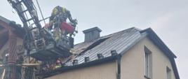 Na zdjęciu widać rozłożony podnośnik hydrauliczny z JRG 2 w Tarnowie oraz pracujących ratowników zabezpieczających uszkodzone poszycie dachu.