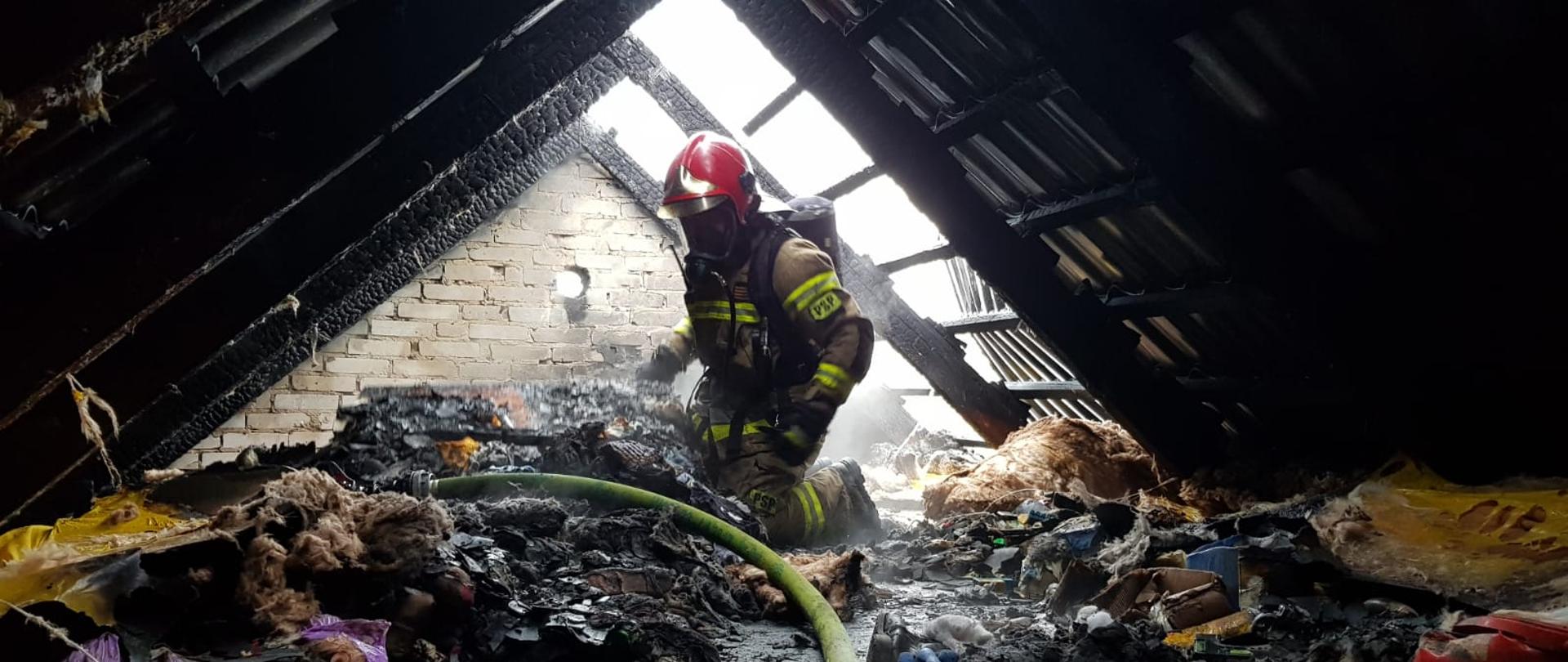 rażak w ubraniu bojowym oraz aparacie powietrznym podczas działań na spalonym poddaszu
