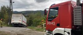Samochód ciężarowy poza drogą a obok samochód pożarniczy