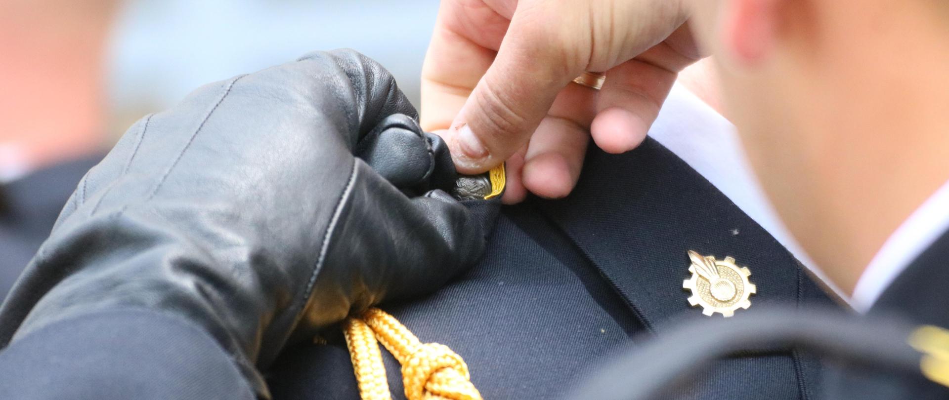 Promowani ściągają pochewki z pagonów zasłaniające nowe stopnie służbowe 