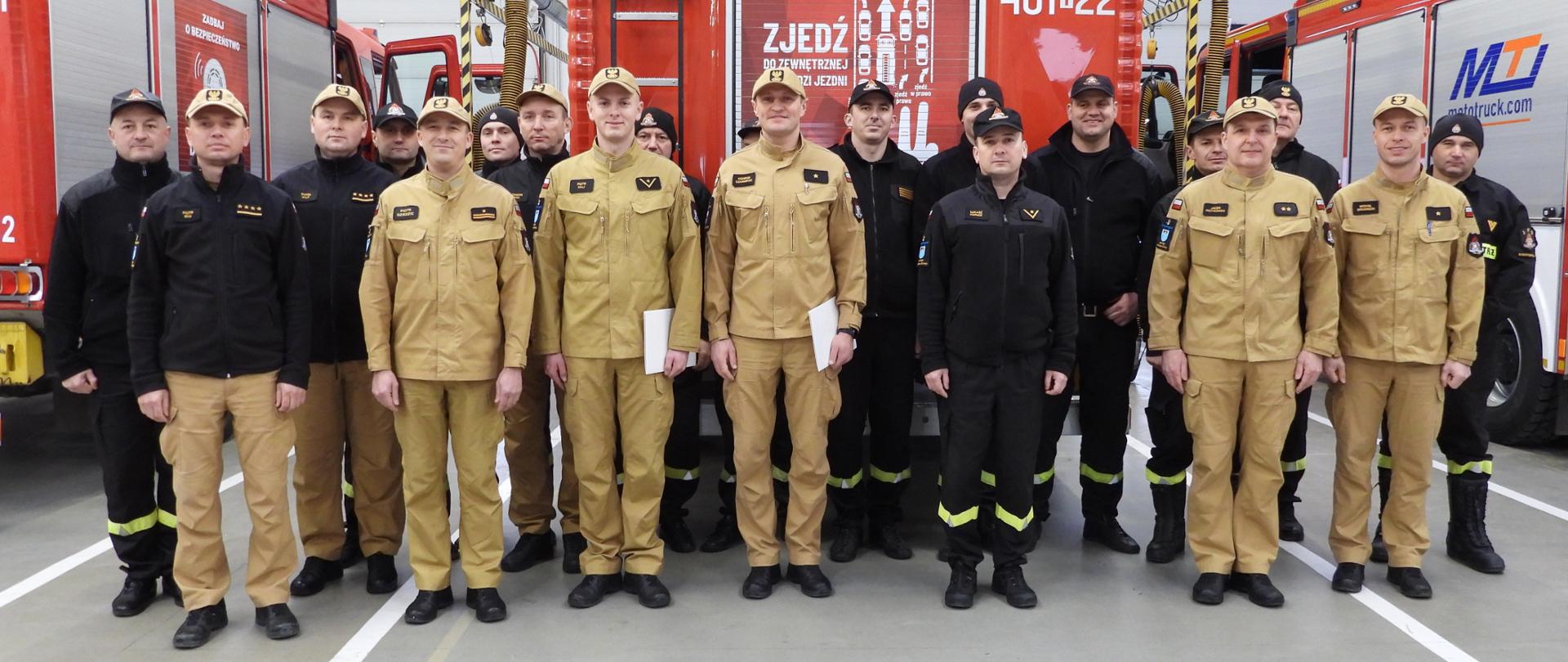 Zdjęcie grupowe strażaków na tle samochodu pożarniczego. 