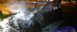 Zdjęcie przedstawia całkowicie spalony samochód osobowy, który zaparkowany jest na parkingu przy ul. Wieniawskiego w Koninie. 