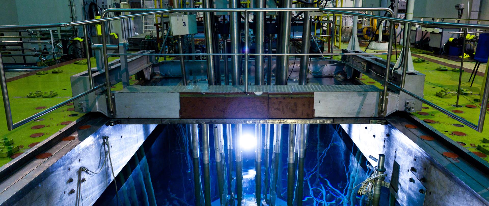 Zdjęcie przedstawia basen reaktora badawczego Maria. Na zdjęciu widać basen, w którym znajduje się reaktor wraz z instalacjami technicznymi