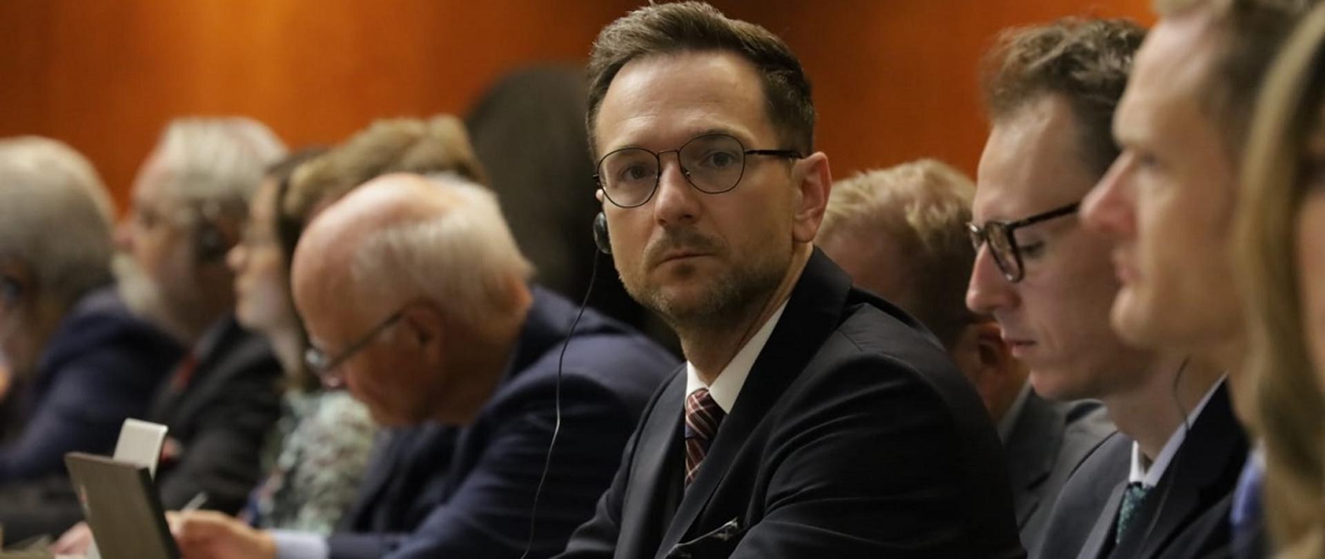 Minister rozwoju i technologii Waldemar Buda siedzący przy stole podczas posiedzenia 12 Konferencji WTO, obok ministra siedzą przedstawicieli innych państw 