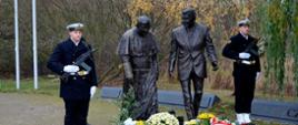 Żołnierze Marynarki Wojennej Rzeczypospolitej Polskiej stoją obok pomników Jana Pawła II oraz Ronalda Reagana. Pod pomnikami leżą kwiaty. 