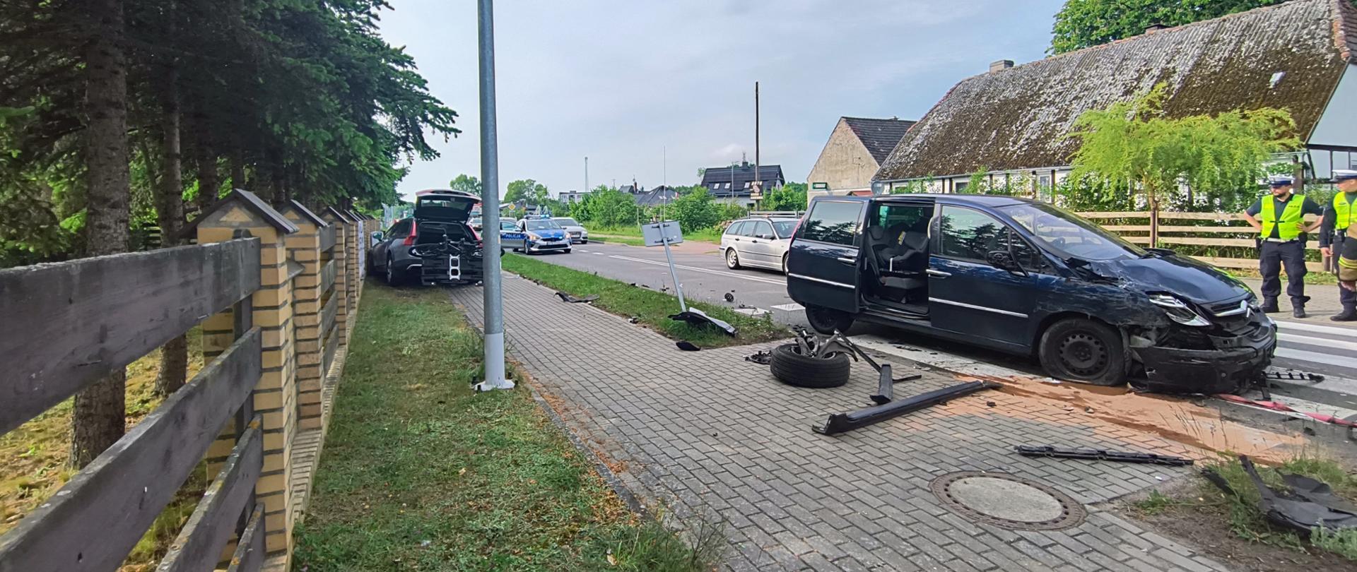 Na drodze widać rozbite auto marki citroen, w oddali na poboczu stoi auto marki Volvo biorące udział w kolizji.