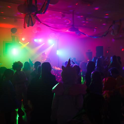 uczniowie bawiący się na balu, dużo kolorowych migających świateł