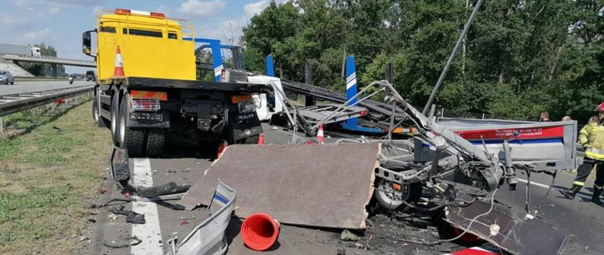 Części pojazdów rozsypane na jezdni w tle ciężarówka pomocy drogowej