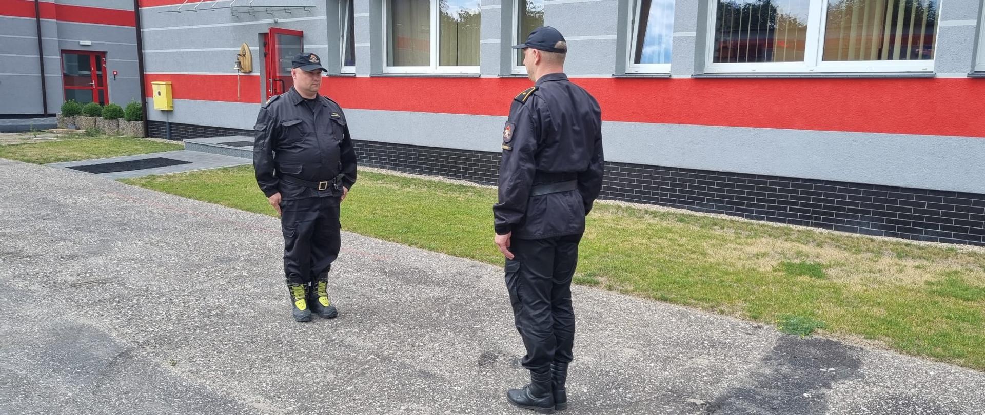 dwóch strażaków stoi na przeciwko siebie