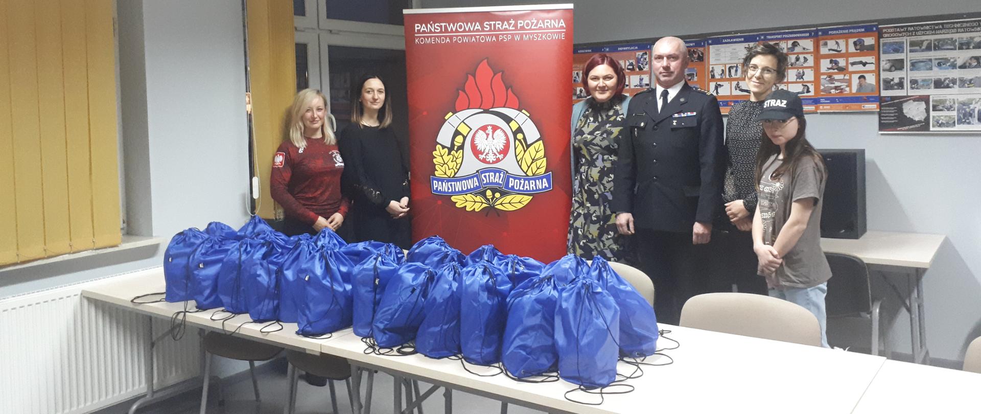 Zdjęcie przedstawia spotkanie mikołajkowe Komendanta Powiatowego PSP w Myszkowie z przedstawicielami grupy Danone p. Magdaleną Konowrocka i p. Moniką Wieczorek, prezes zarządu LKS Myszków p. Irminą Flak oraz założycielką fundacji poMocna p. Magdaleną Zaczkowską. 