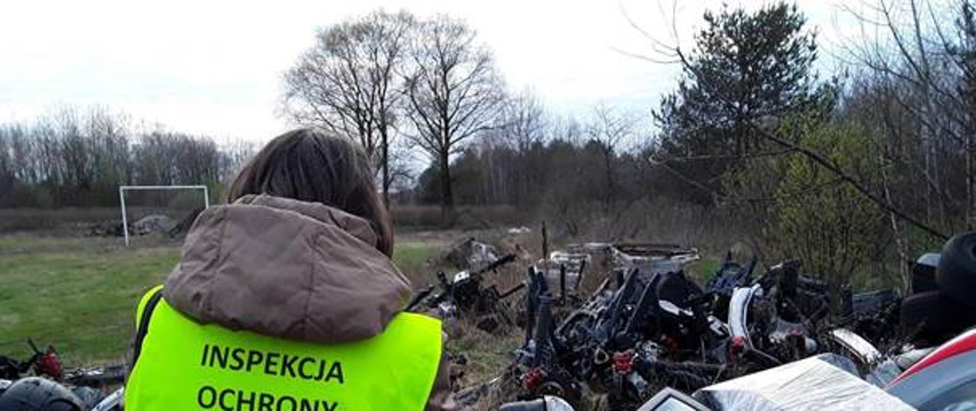 Człowiek patrzący na resztki złomowanych samochodów