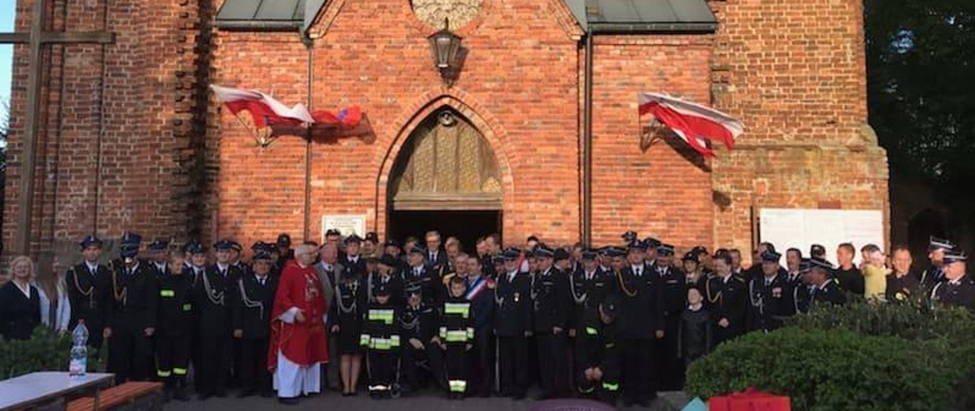 Uczestnicy mszy zebrani przed murowanym kościołem