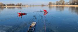 Na zdjęciu widać 2 strażaków podczas ćwiczeń na zamarzniętym akwenie wodnym