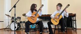 
Wykonawcy przy instrumentach na scenie w sali koncertowej podczas Uroczystego Koncertu Absolwentów