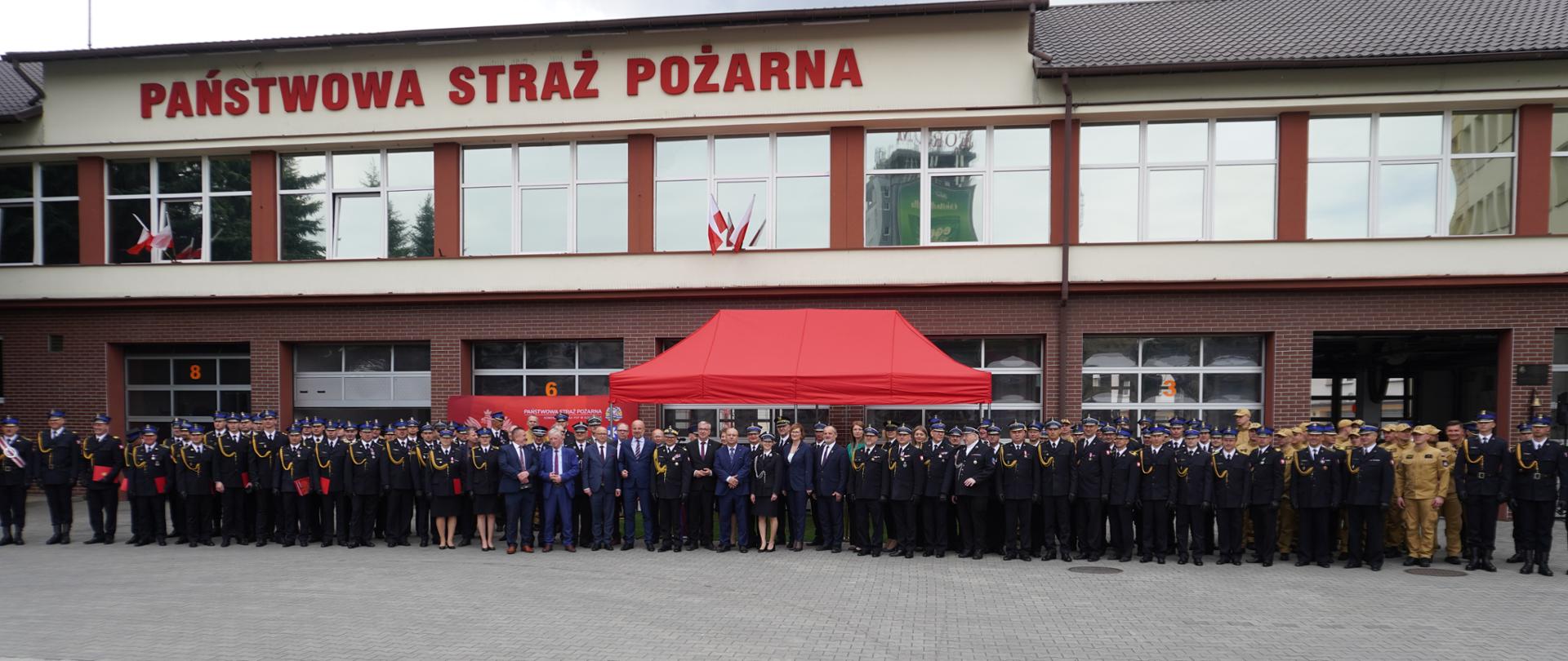 Wspólne zdjęcie uczestników Powiatowych Obchodów Dnia Strażaka przed budynkiem Jednostki Ratowniczo-Gaśniczej nr 1 Komendy Miejskiej PSP w Rzeszowie. Na fotografii widoczni są strażacy, zaproszeni goście oraz przedstawiciele służb współpracujących.