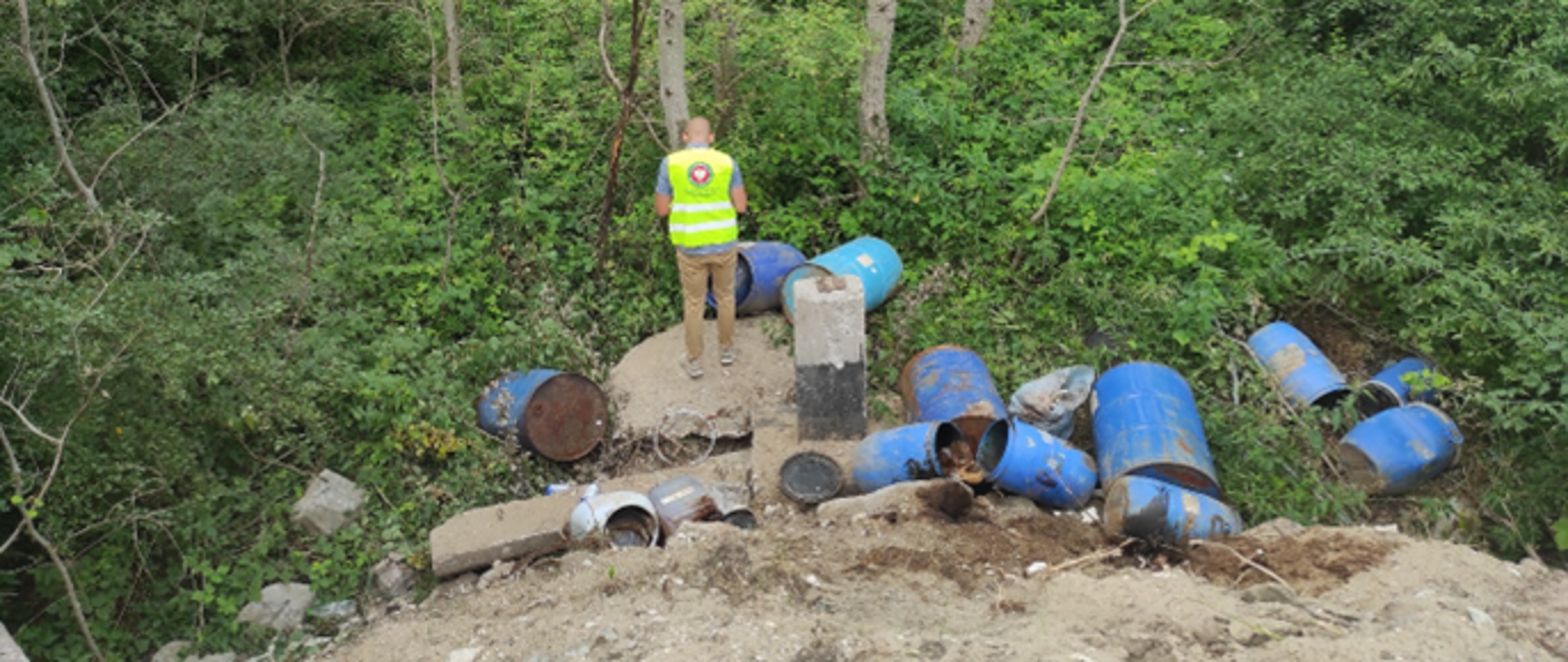 Pracownik Inspekcji Ochrony Środowiska badający miejsce nielegalnego magazynowania odpadów