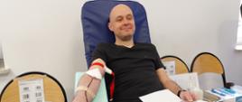 Na zajęciu widoczny mężczyzna w czarnej koszulce i w jeansach siedzący na fotelu na sali oddający krew podczas akcji zbiórki krwi zorganizowanej przez Klub Honorowych Dawców Krwi Polskiego Czerwonego Krzyża przy Komendzie Powiatowej Państwowej Straży Pożarnej w Gorlicach 