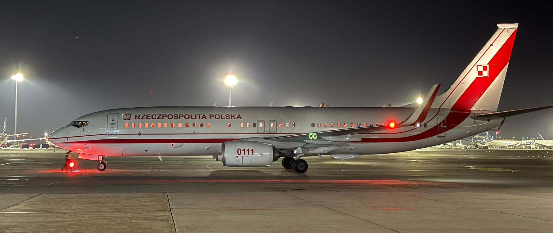 Boeing w biało-czerwonych barwach z napisem Rzeczpospolita Polska stoi na płycie lotniska. Zdjęcie zrobione w nocy.