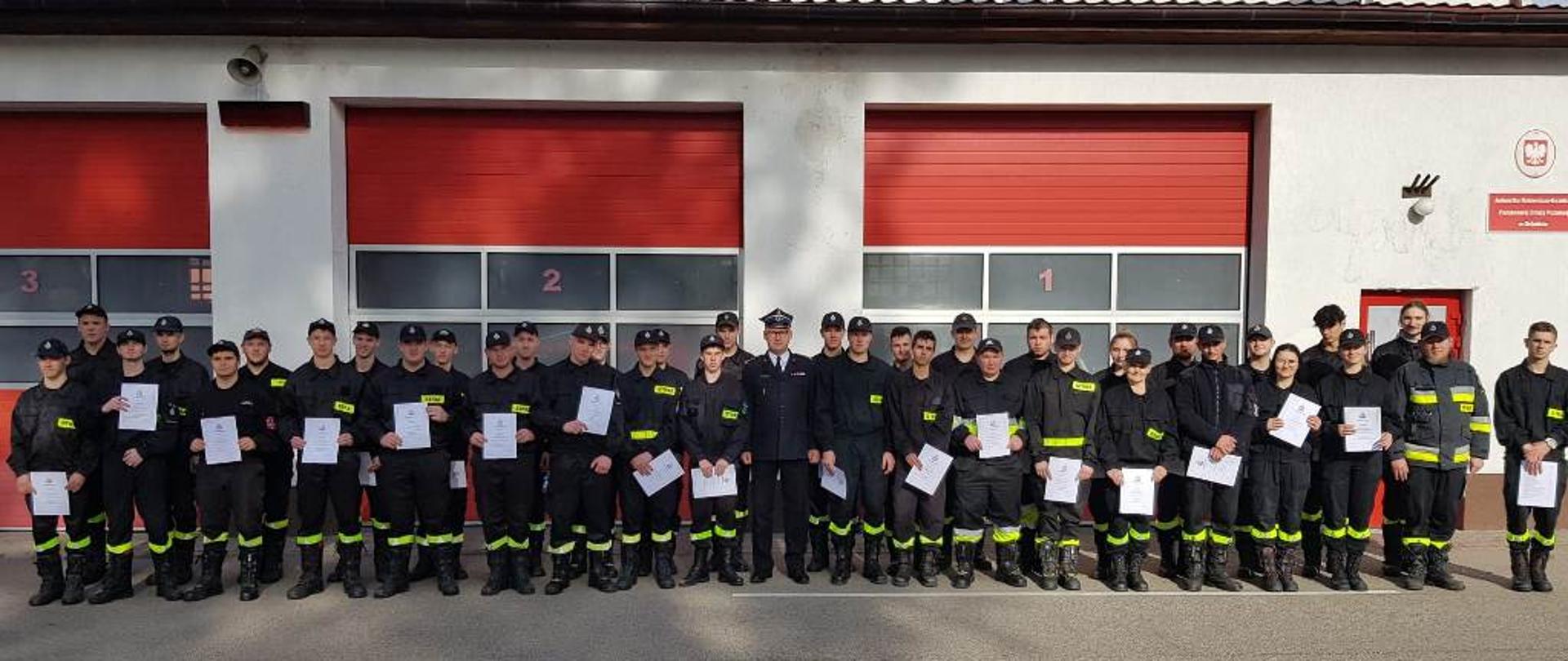 Strażacy po egzaminie prezentują zdobyte zaświadczenia. 