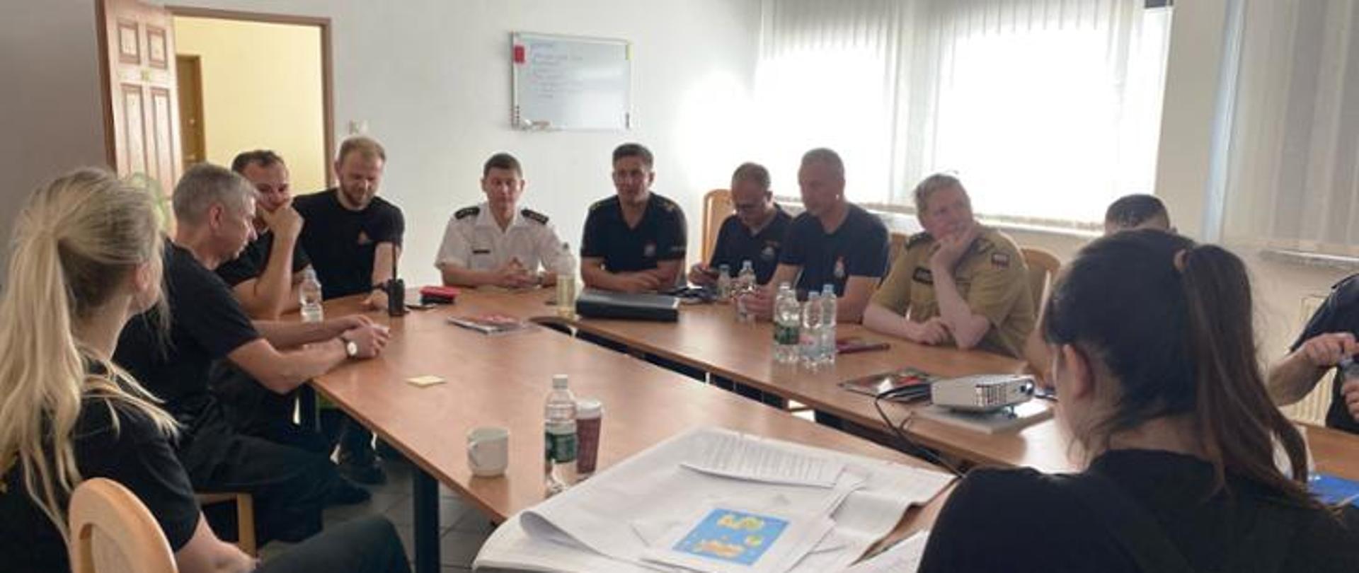 Uczestnicy warsztatów siedzą wokół owalnego stołu.