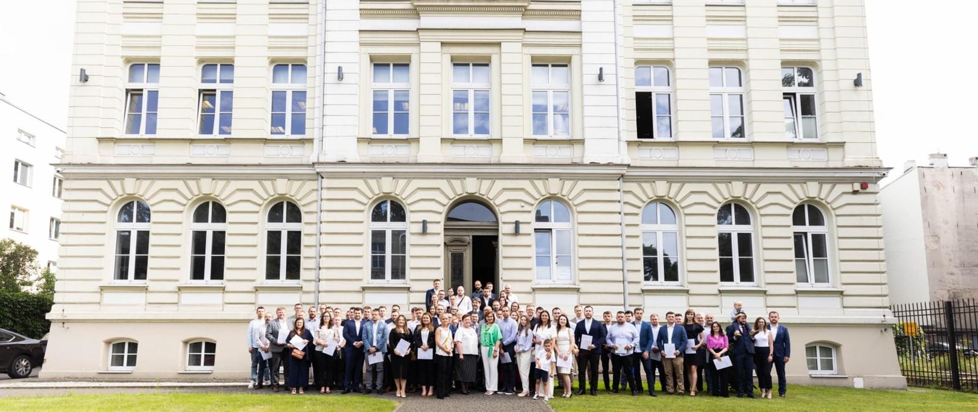 Pamiątkowa fotografia uczestników uroczystości przed budynkiem Łódzkiej Okręgowej Izbie Inżynierów Budownictwa 