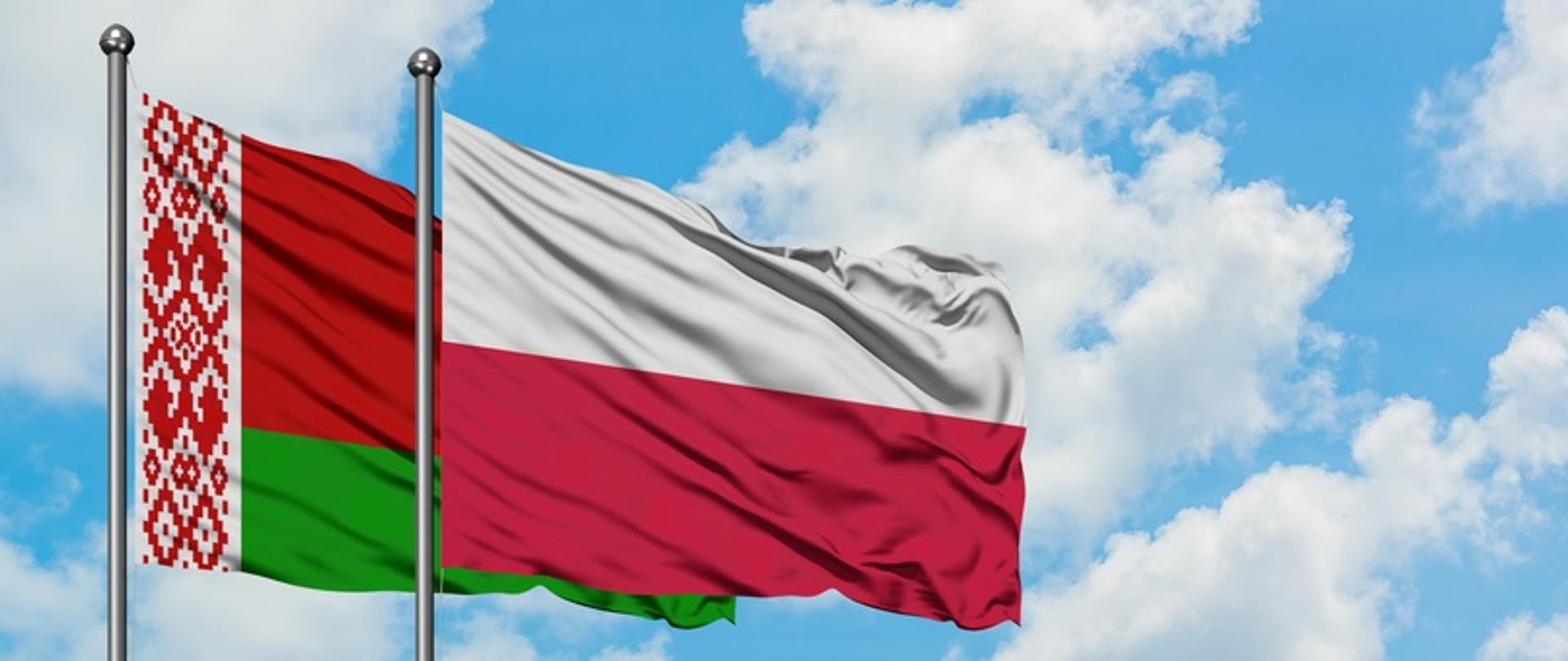 Flaga Polski i Białorusi powiewa na tle błękitnego nieba.