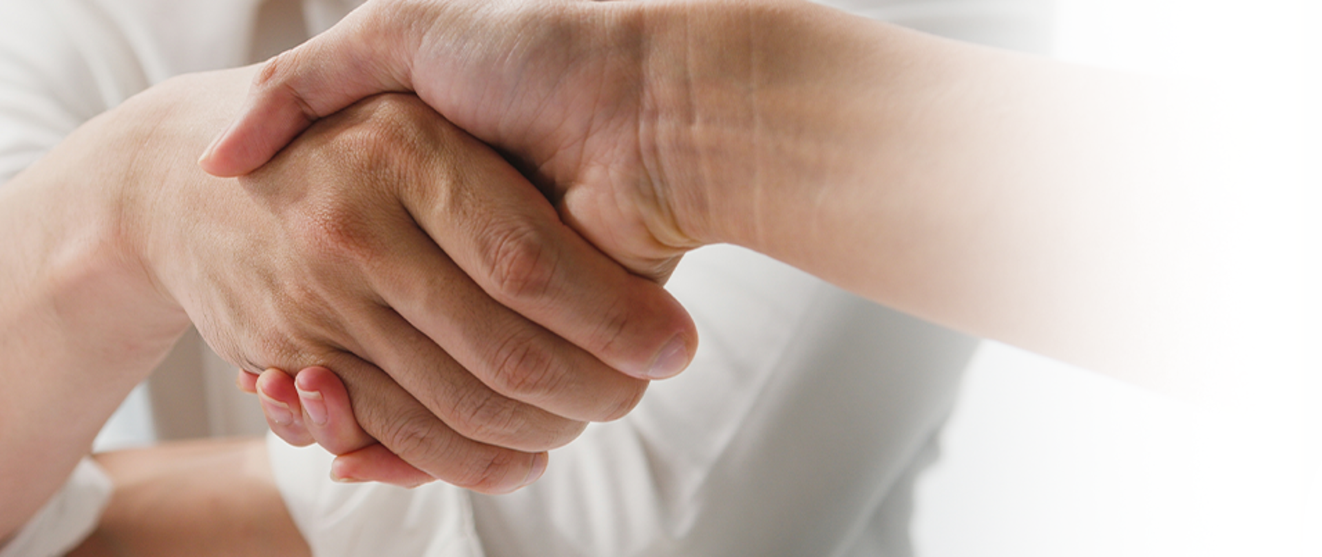 zdjęcie przedstawia po lewej stronie dłonie w uścisku powitalnym, po prawej stronie na beżowym tle z zarysem teczki napis Praca