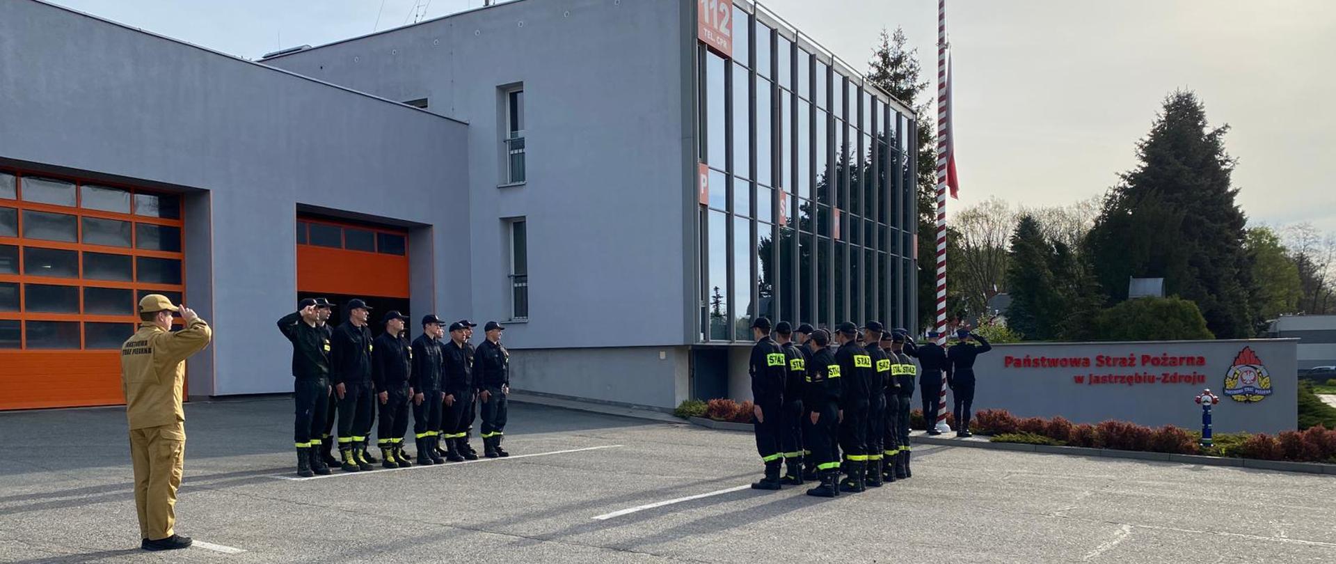 Strażacy wraz z dowódcą podczas uroczystego podniesienia Flagi Państwowej Rzeczypospolitej Polskiej przed siedzibą Komendy Miejskiej PSP w Jastrzębiu-Zdroju.