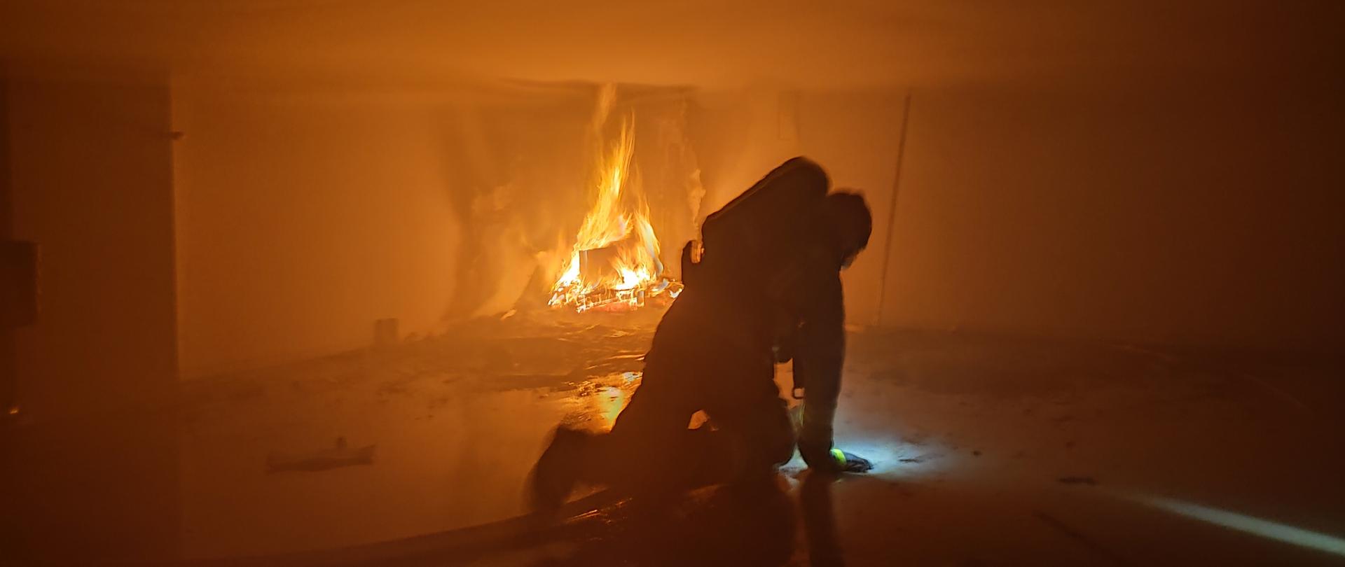 Strażak poruszający się w pomieszczeniu objętym pożarem