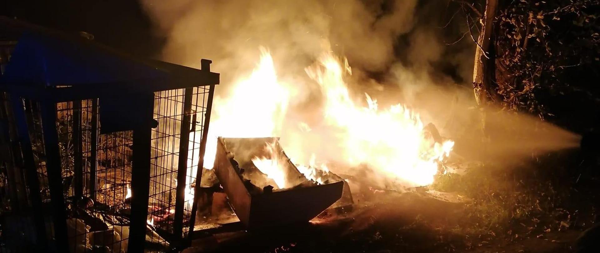 Zdjęcie zrobione nocą. Widać duże płomienie, unosi się dym.