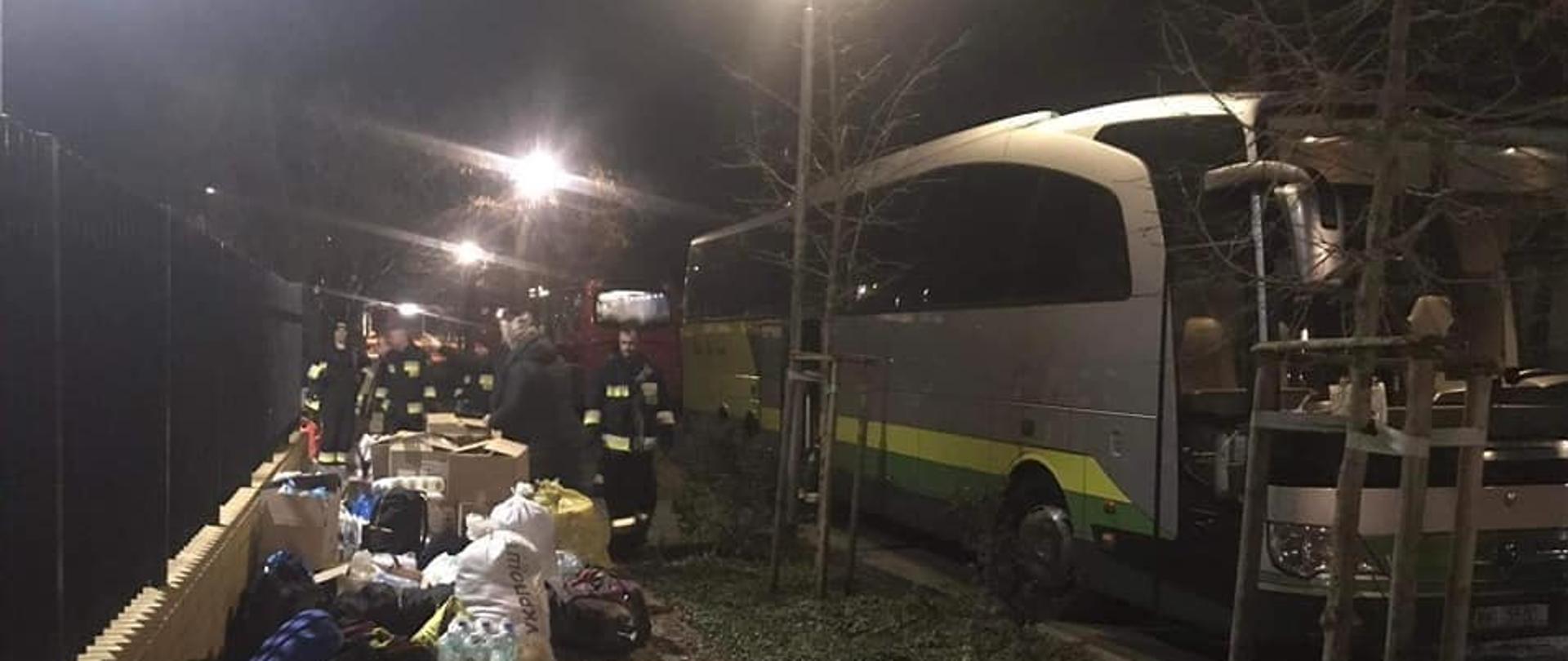 Na zdjęciu znajduję się autobus, który stoi na drodze obok niego stoją ludzie i leżą jakieś przedmioty.