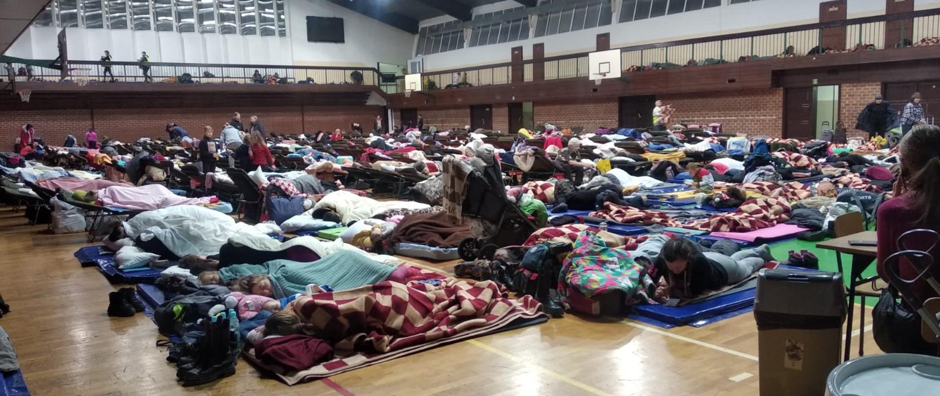 Uchodźcy tymczasowo przebywający w hali sportowej.