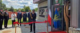Komendant Główny PSP nadbryg. Wojciech Kruczek dokonuje przecięcia wstęgi jako drugi z zaproszonych gości, co symbolizuje zakończenie etapu inwestycyjnego i początek działalności operacyjnej nowej komendy. Obecni są także przedstawiciele władz samorządowych i komitetu fundacji sztandaru.