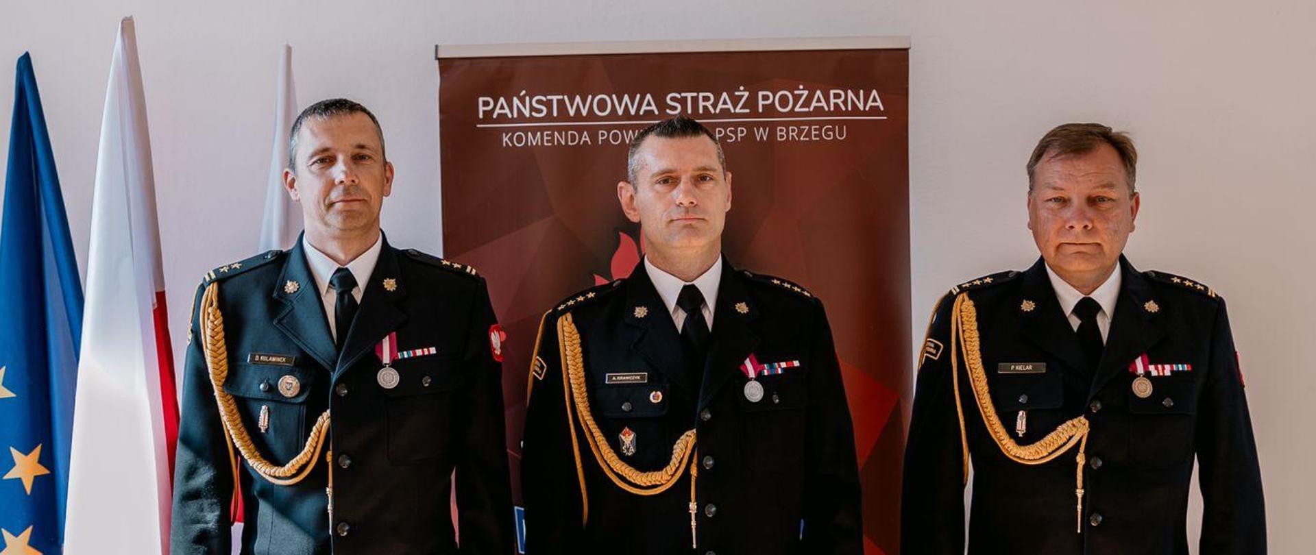 Trzech funkcjonariuszy Państwowej Straży Pożarnej podczas powierzania pełnienia obowiązków zastępcy komendanta powiatowego.
