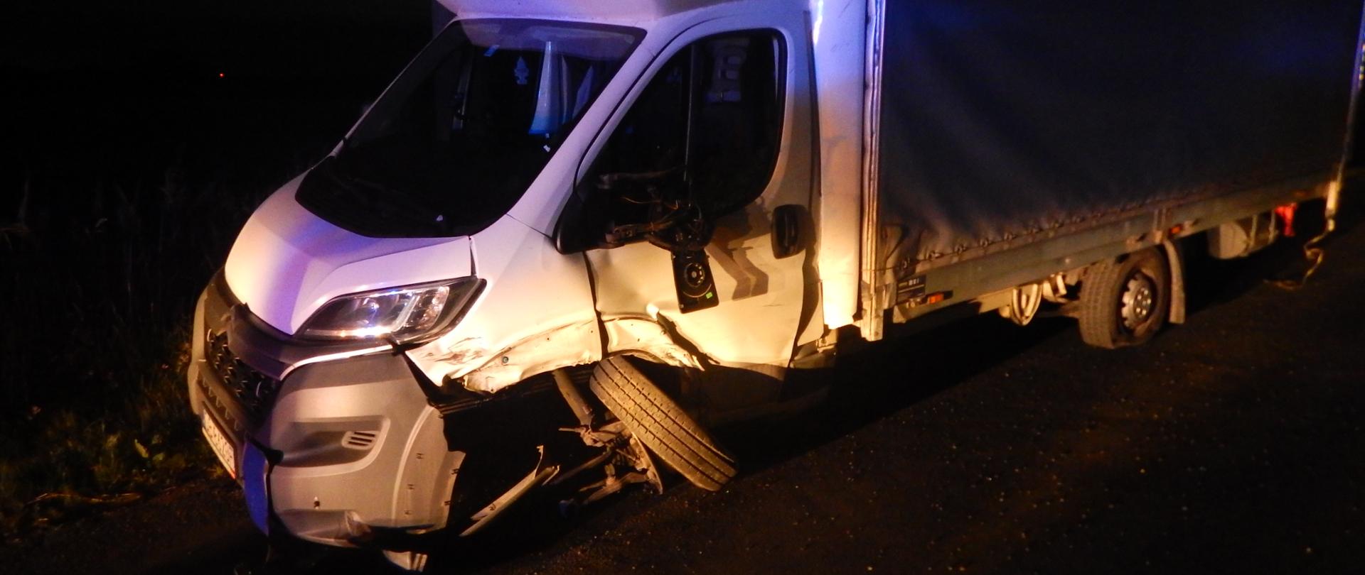 Zdjęcie przedstawia biały samochód dostawczy po wypadku drogowym. Samochód ma uszkodzony przedni prawy bok.