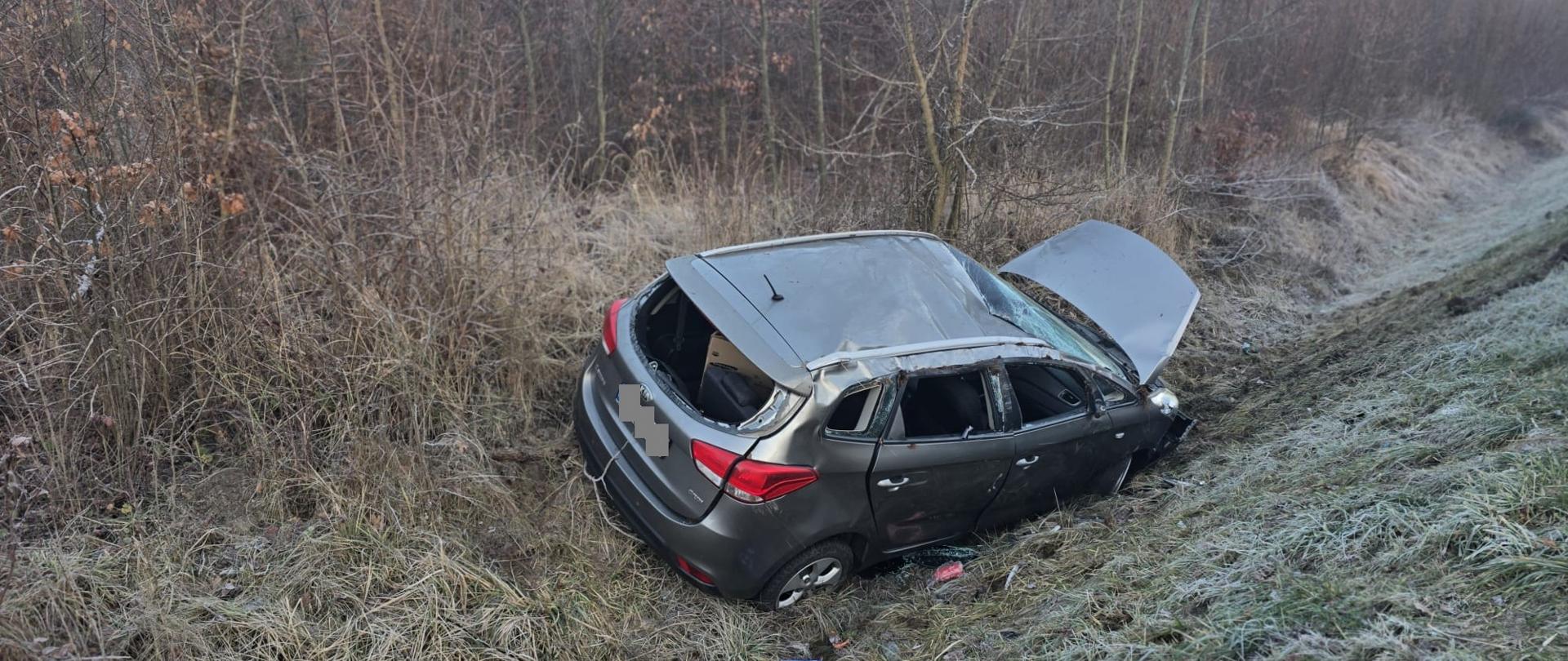Szary samochód po dachowaniu w rowie, otwarta maska