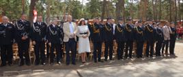 Obóz szkoleniowo-wypoczynkowy MDP w Brennie. Na placu apelowym trwa msza święta. Na pierwszym planie goście zaproszeni na uroczystość. Stoją w szeregu. Wśród nich jest minister Jan Dziedziczak, Wielkopolski Komendant Wojewódzki PSP, dyrektor Biura Rzecznika Praw Dziecka i inni.