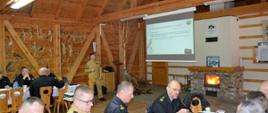 Strażak omawia zagadnienia wyświetlane na rzutniku multimedialnym podczas narady kadry kierowniczej Państwowej Straży Pożarnej województwa pomorskiego. 