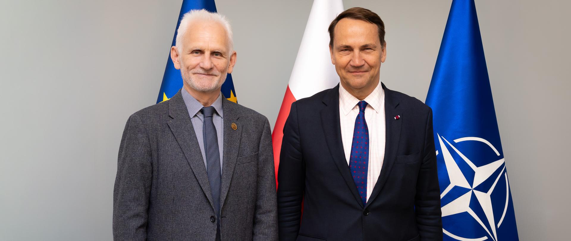 Wicepremier, Minister Spraw Zagranicznych Radosław Sikorski spotkał się z Alesiem Białackim. Obaj stoją na tle flag: UE, Polski oraz NATO