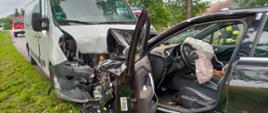 Samochód osobowy Citroën oraz samochód dostawczy Renault Master po zderzeniu. Na drugim pasie jezdni karetka pogotowia, na poboczu przydrożne drzewa. Za samochodem Renault Master w oddali widać samochód strażacki.