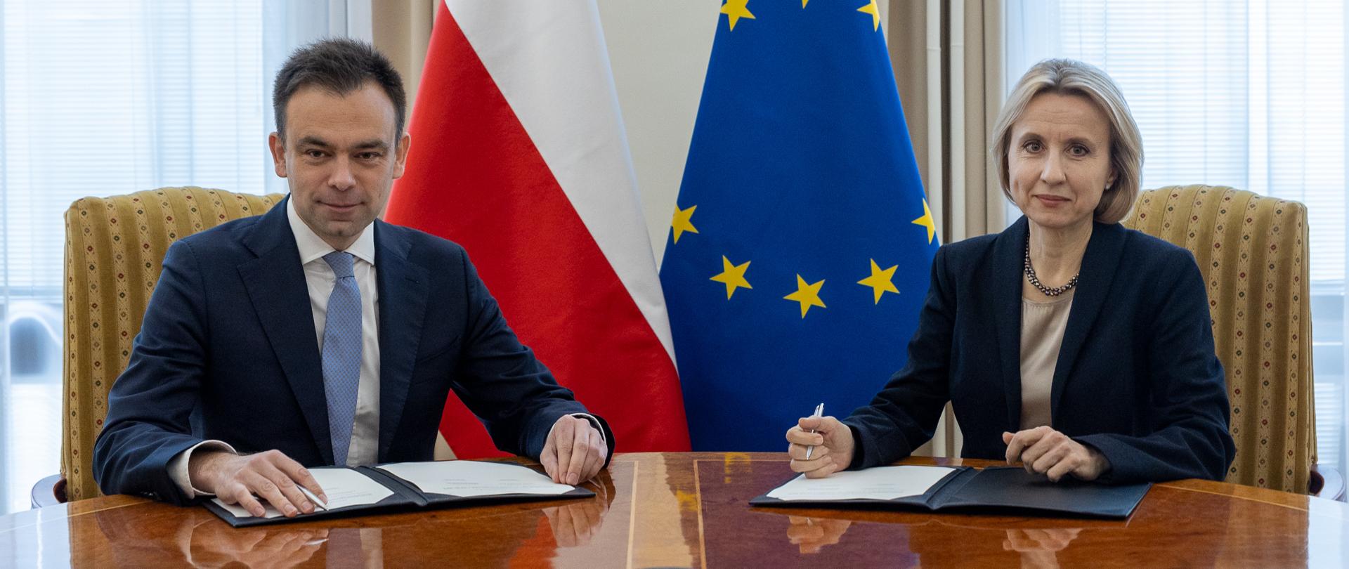 Uśmiechnięci minister finansów Andrzej Domański i wiceprezes EBI prof. Teresa Czerwińska przed podpisaniem umowy